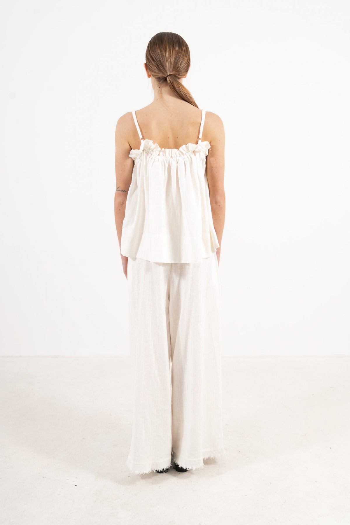 The refined back view of the MOCHA Adeline top in fine soft cotton, displaying a clean, elegant rear layout arranged flat on a polished white floor.
