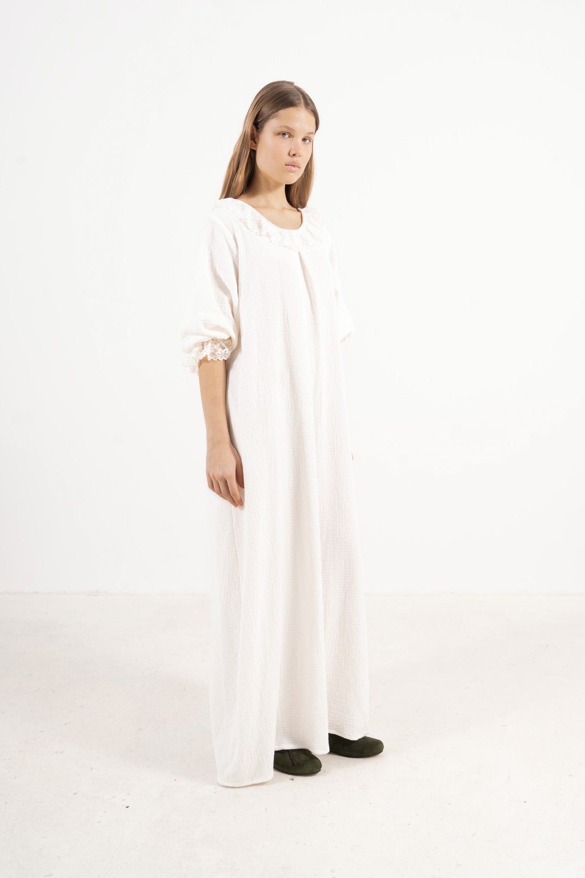 A poetic side angle view of the luxury soft cotton MOCHA Aérienne garment, showcasing its light, timeless silhouette cascading softly against a white backdrop.