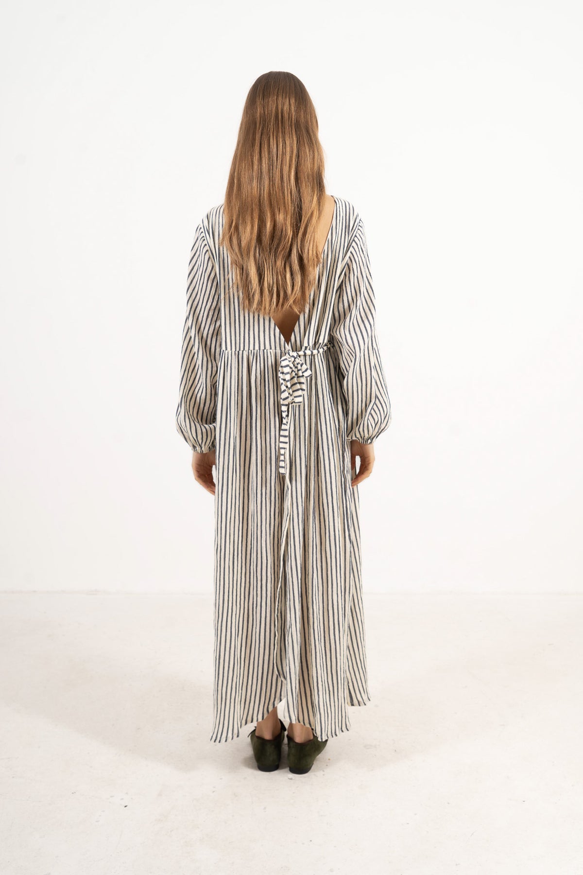 Back view of the timeless long cotton dress on a model, capturing a soft world of lightness, comfort, and gentle days.