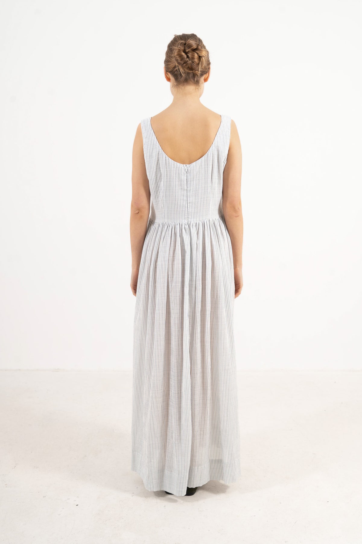 Back view of the timeless long cotton dress on a model, capturing the gentle aesthetic and understated elegance of the piece.