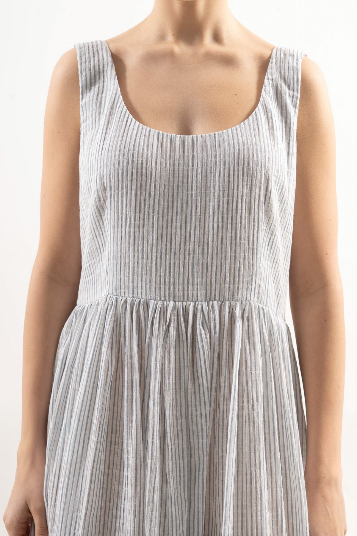 Close-up detail shot focusing on the delicate fine stripe texture and the exquisite embroidery details of the MOCHA cotton dress.