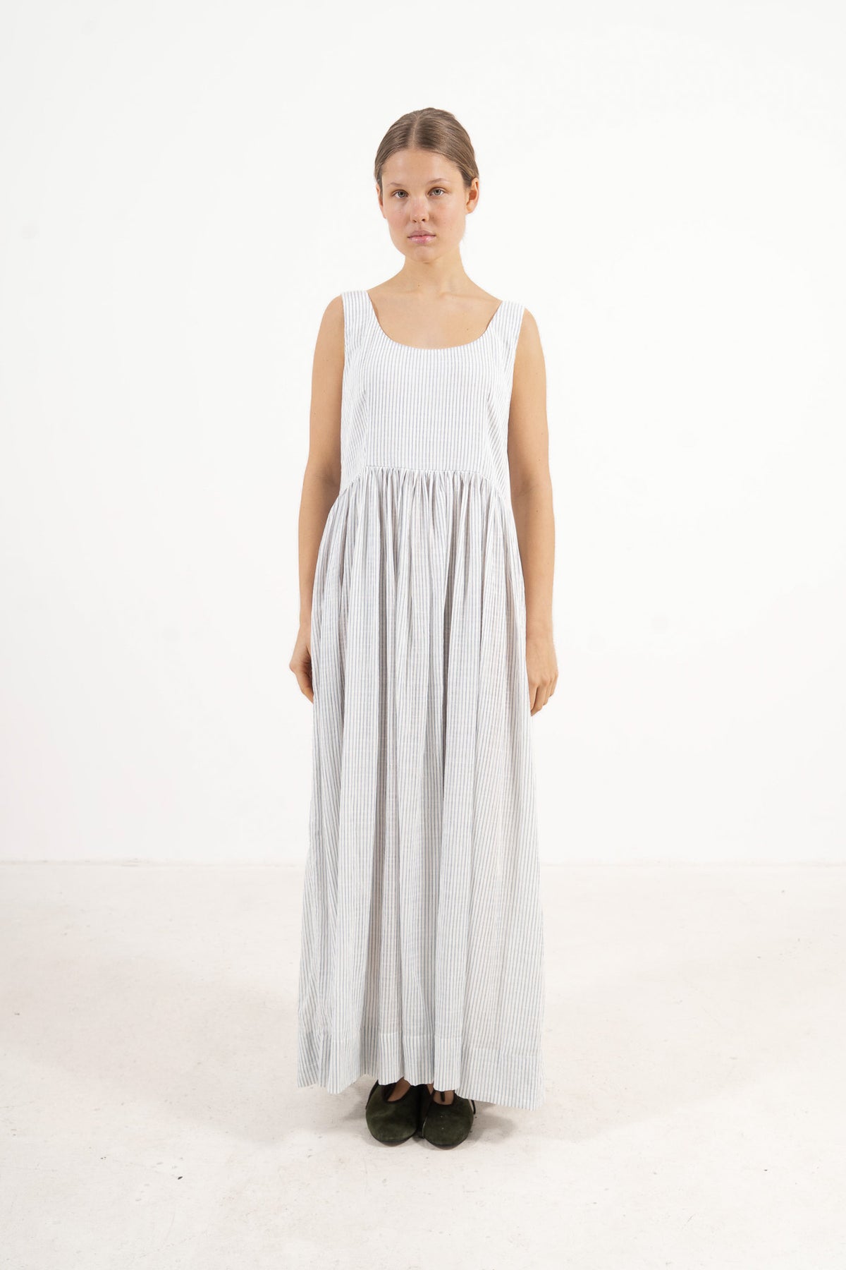 Front view studio portrait featuring a model in the fine-striped Amandine long dress by MOCHA, capturing a soft world of lightness and ease.