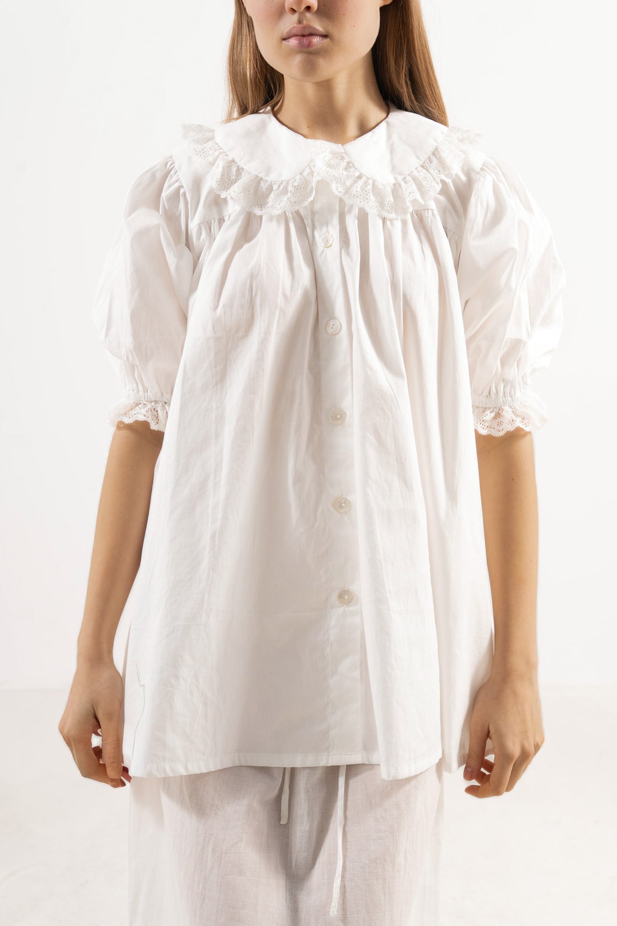 Close-up detail shot focusing on the delicate collar, ruffled details, and premium texture of the pure MOCHA organic cotton fabric.