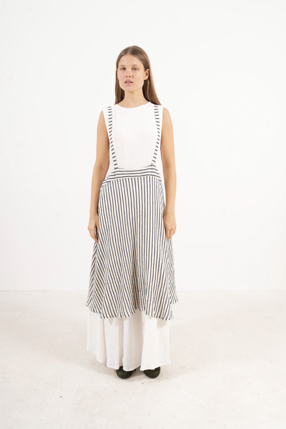 Full-length front view of a fashion model wearing the long MOCHA apron skirt with shoulder straps made from white cotton.