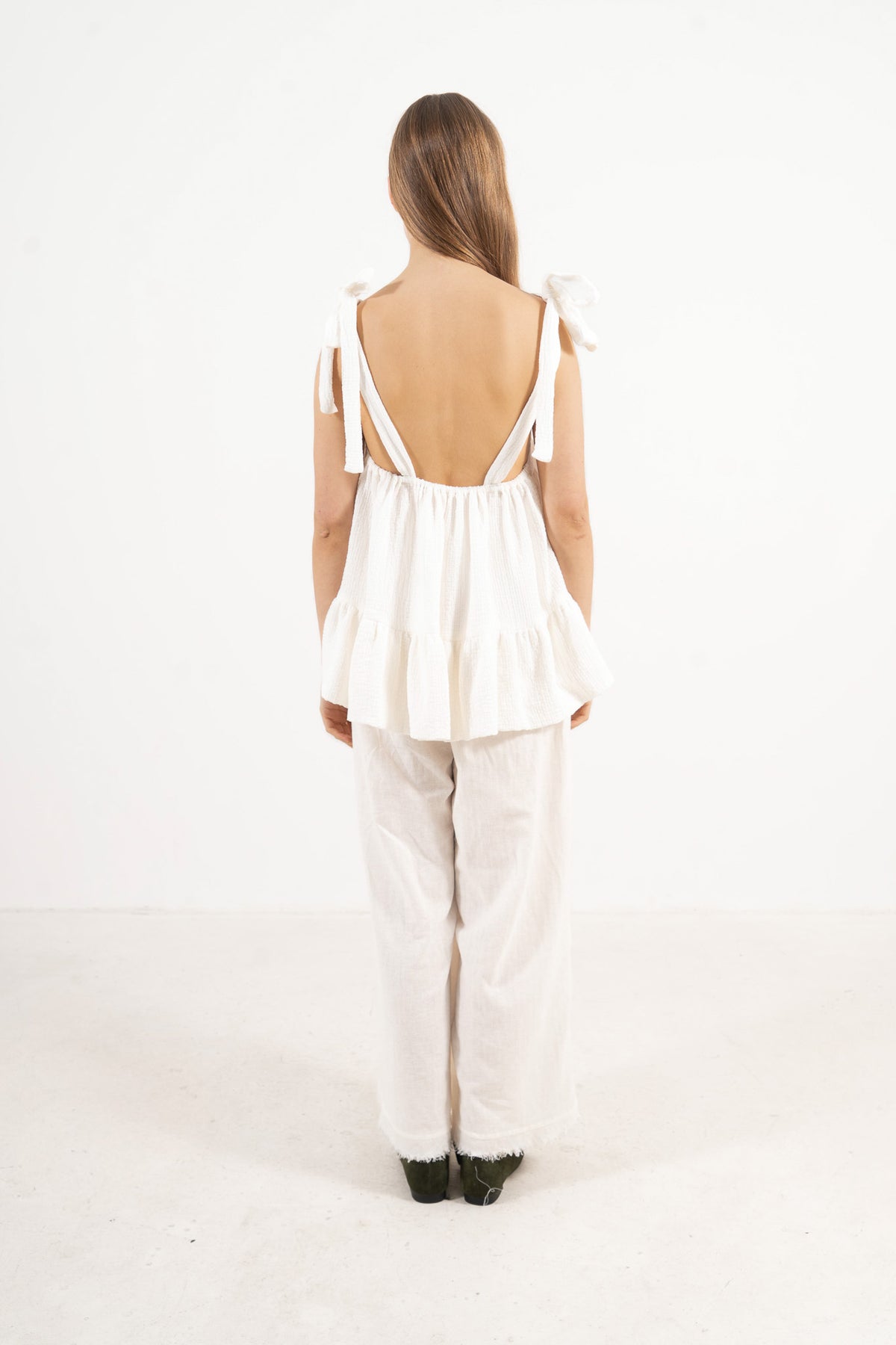 Back view of the timeless cotton top on a model, showcasing the adjustable straps and the graceful minimalist tailoring of the piece.
