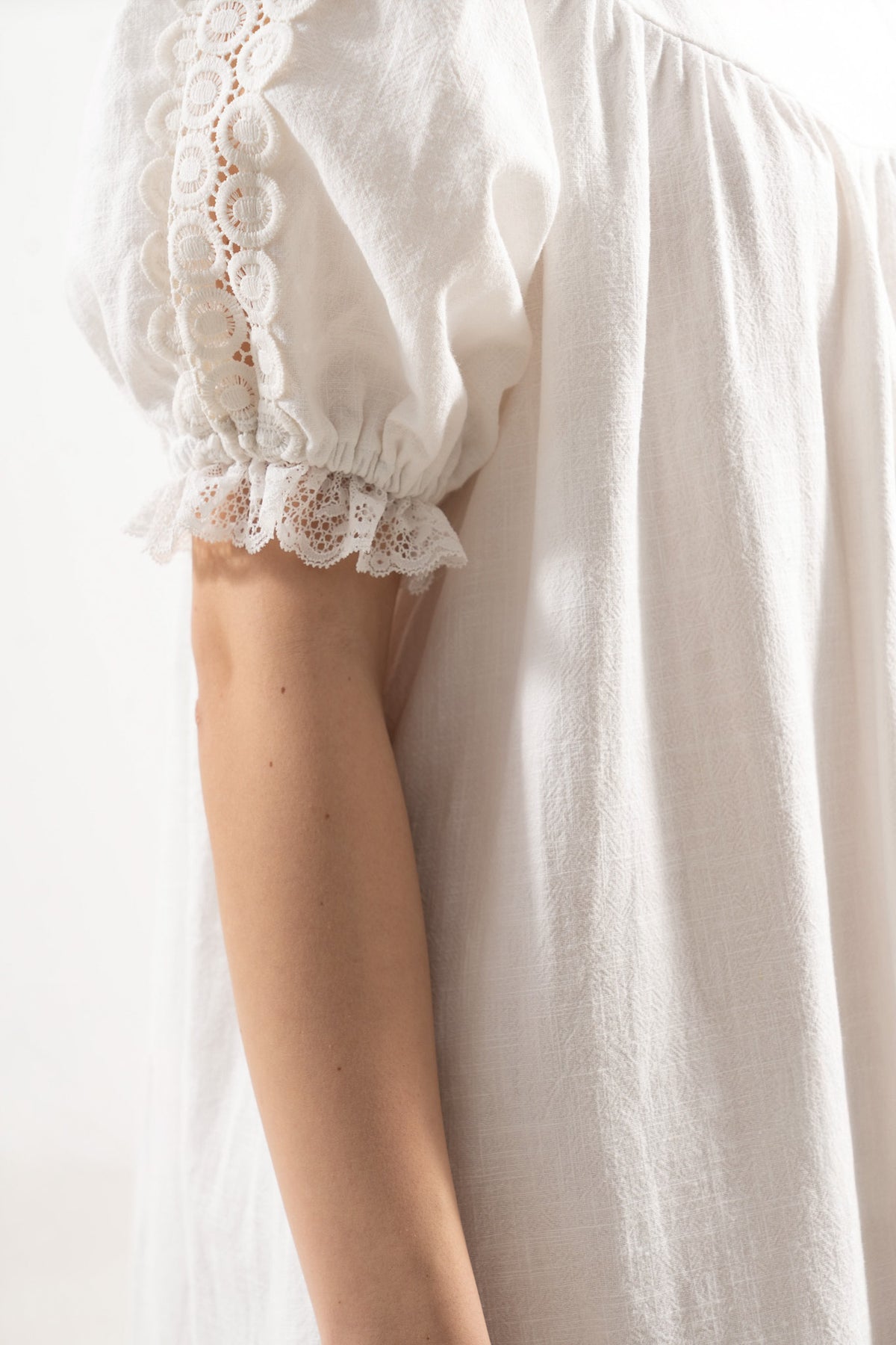 Close-up detail shot focusing on the puff sleeves with delicate ruffled details and refined texture accents of the MOCHA organic cotton fabric.
