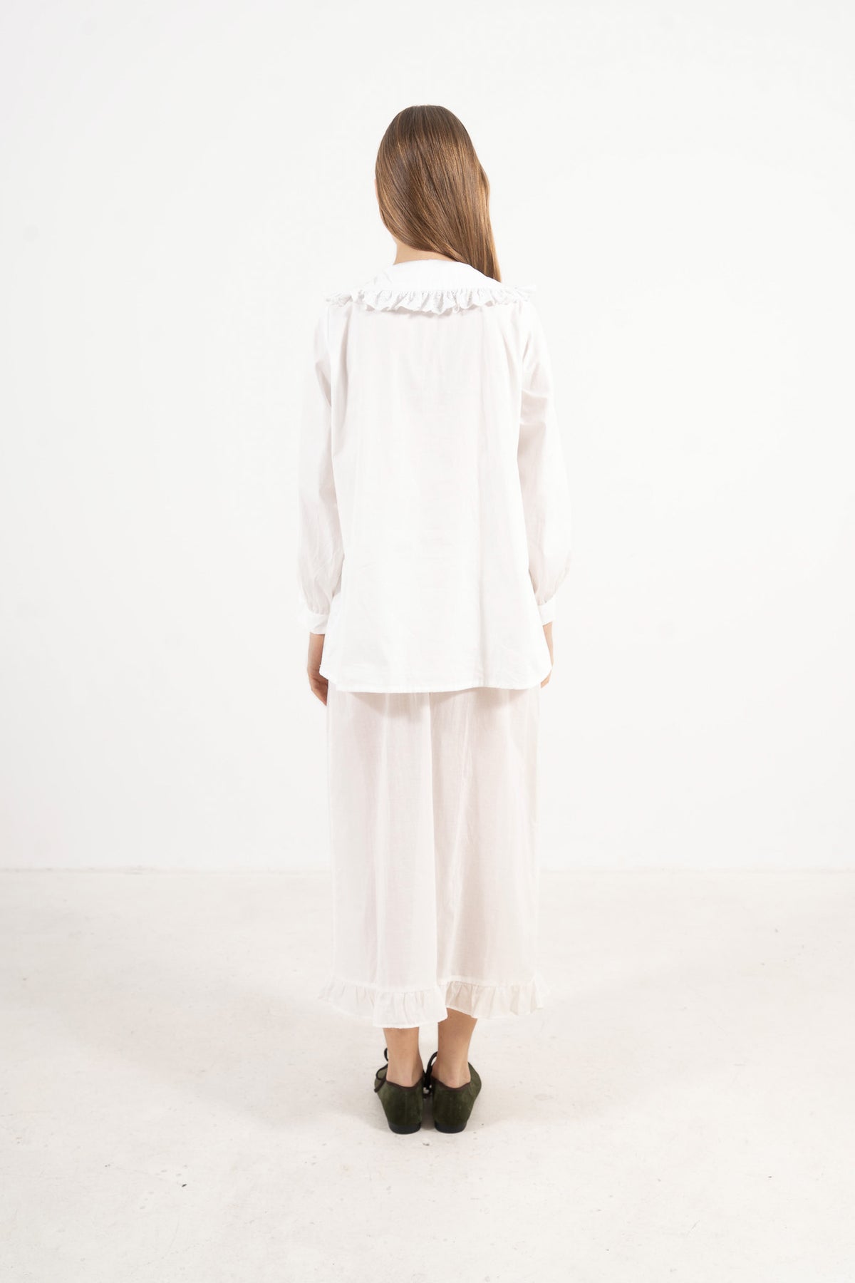 Back view of the timeless organic cotton blouse on a model, capturing a sense of calm ease, understaded femininity, and clean design.