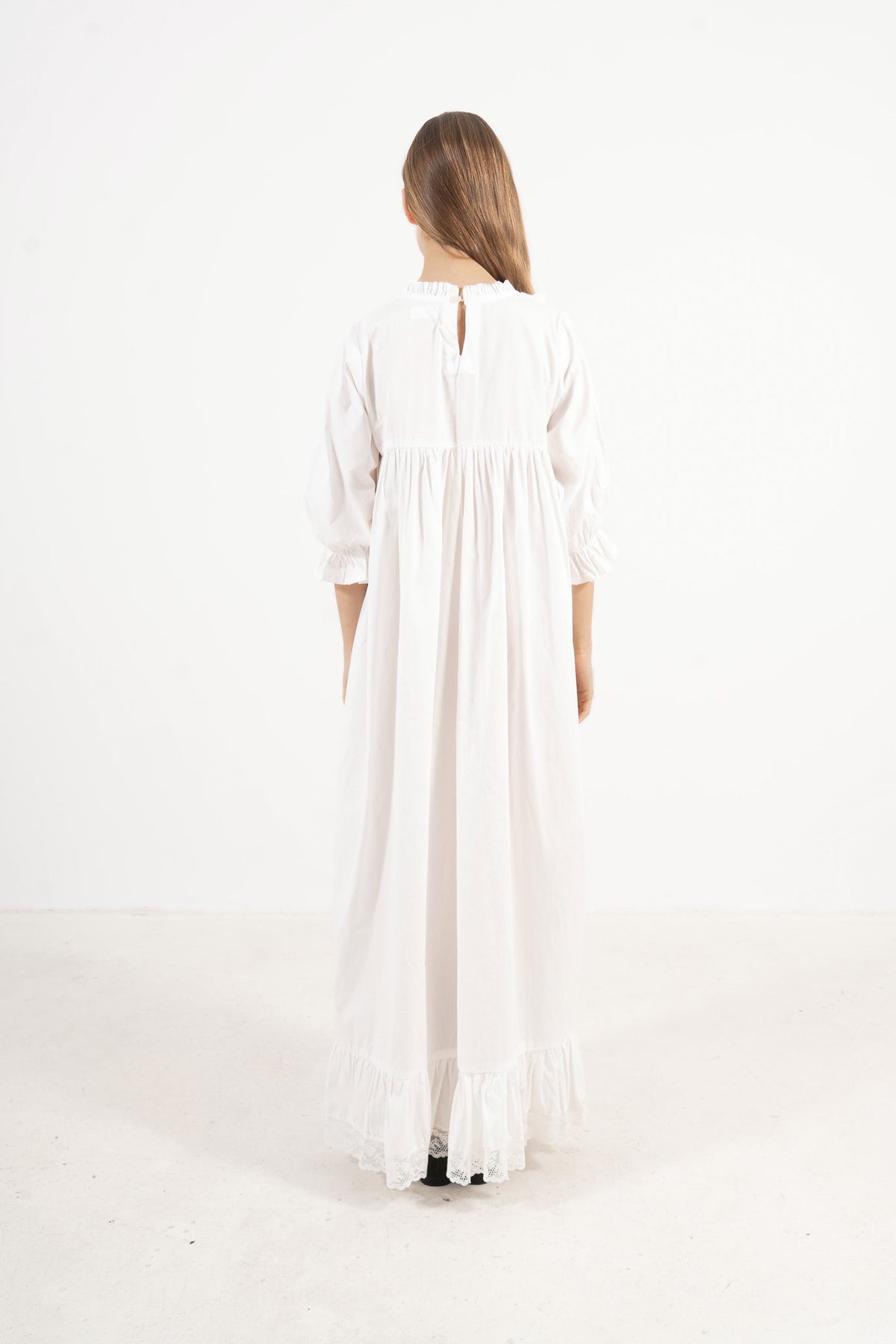 Back view of the timeless long cotton dress on a model, capturing the elegant heritage and seamless tailoring of the piece.