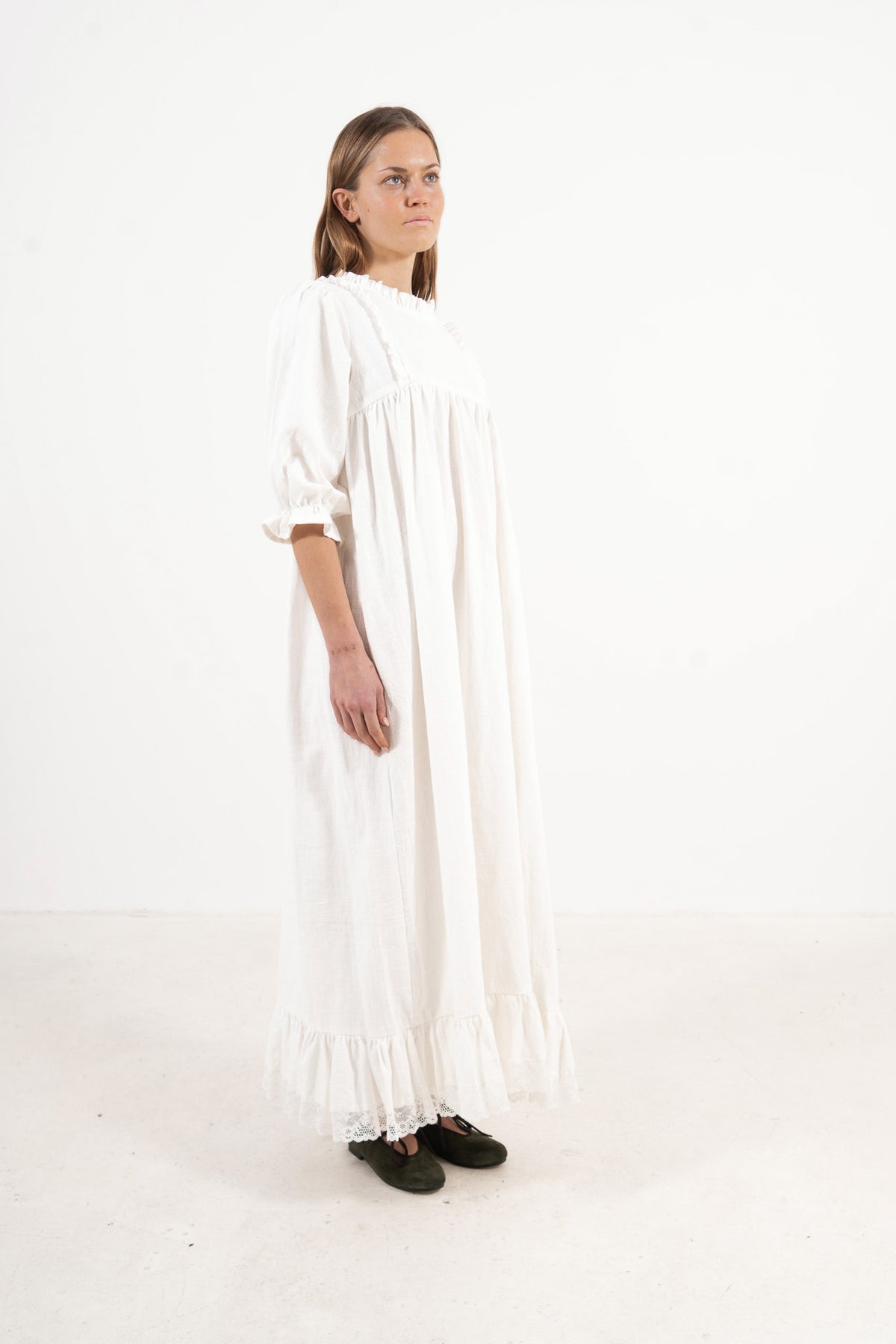 Side profile view of the MOCHA La Robe Noblesse dress showcasing the elegant drape and full-length silhouette.