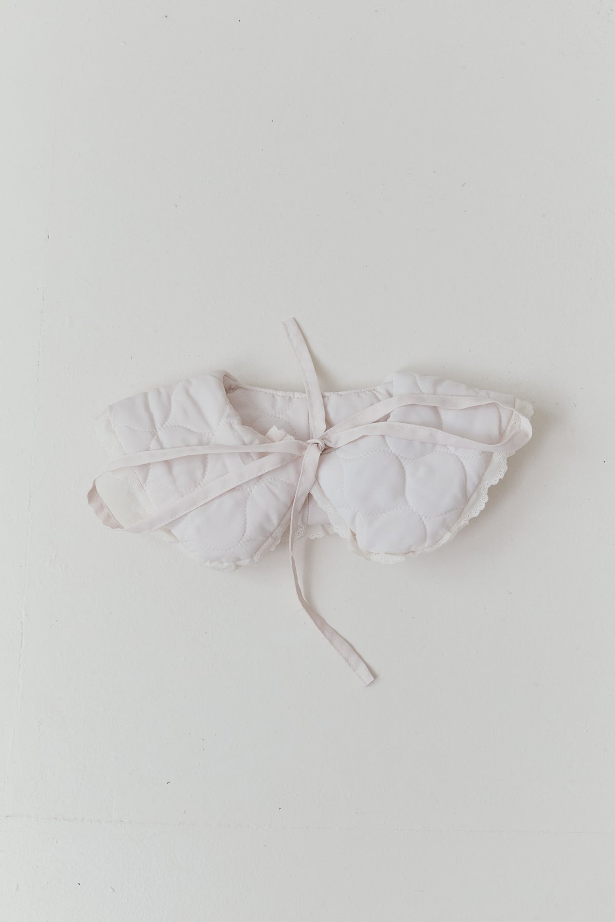 Minimalist flat lay of the MOCHA Le Col de Poésie apron, highlighting the raw beauty of the pure cotton structure and clean silhouette.