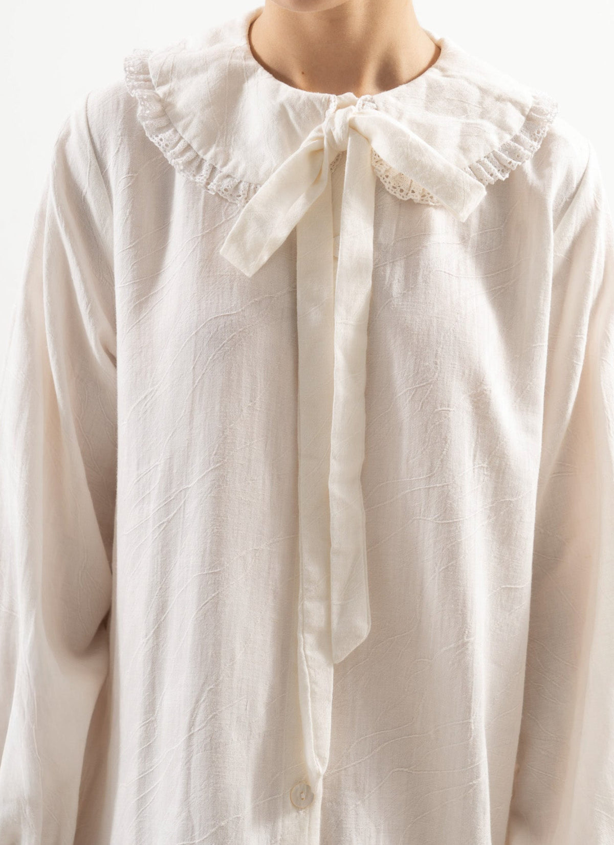 Close-up detail shot focusing on the premium texture of the white organic cotton fabric and the delicate craftsmanship of MOCHA.