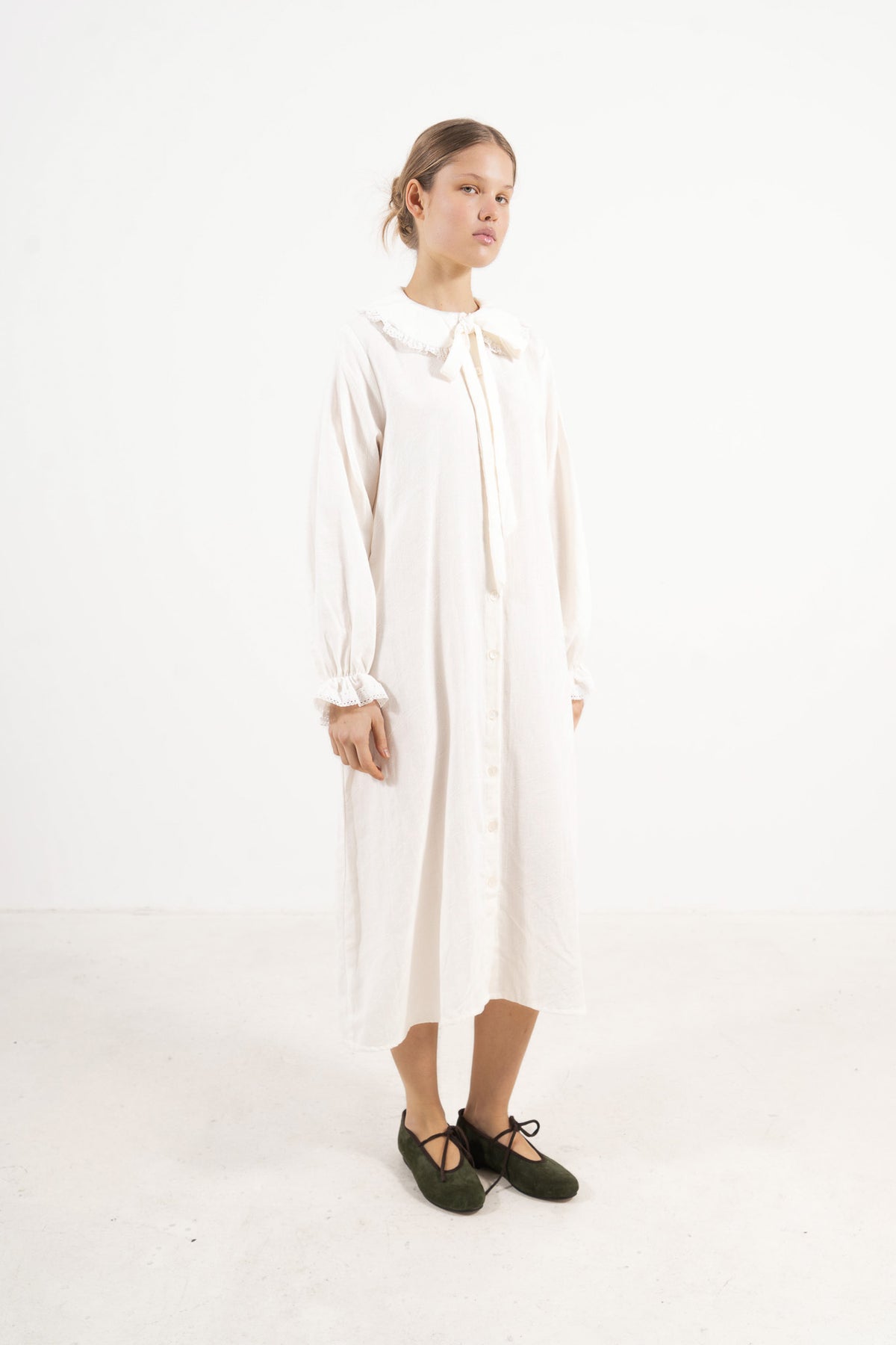 Side profile capture of the white organic cotton dress, emphasizing the flowing movement and airy lightness signature to the collection.