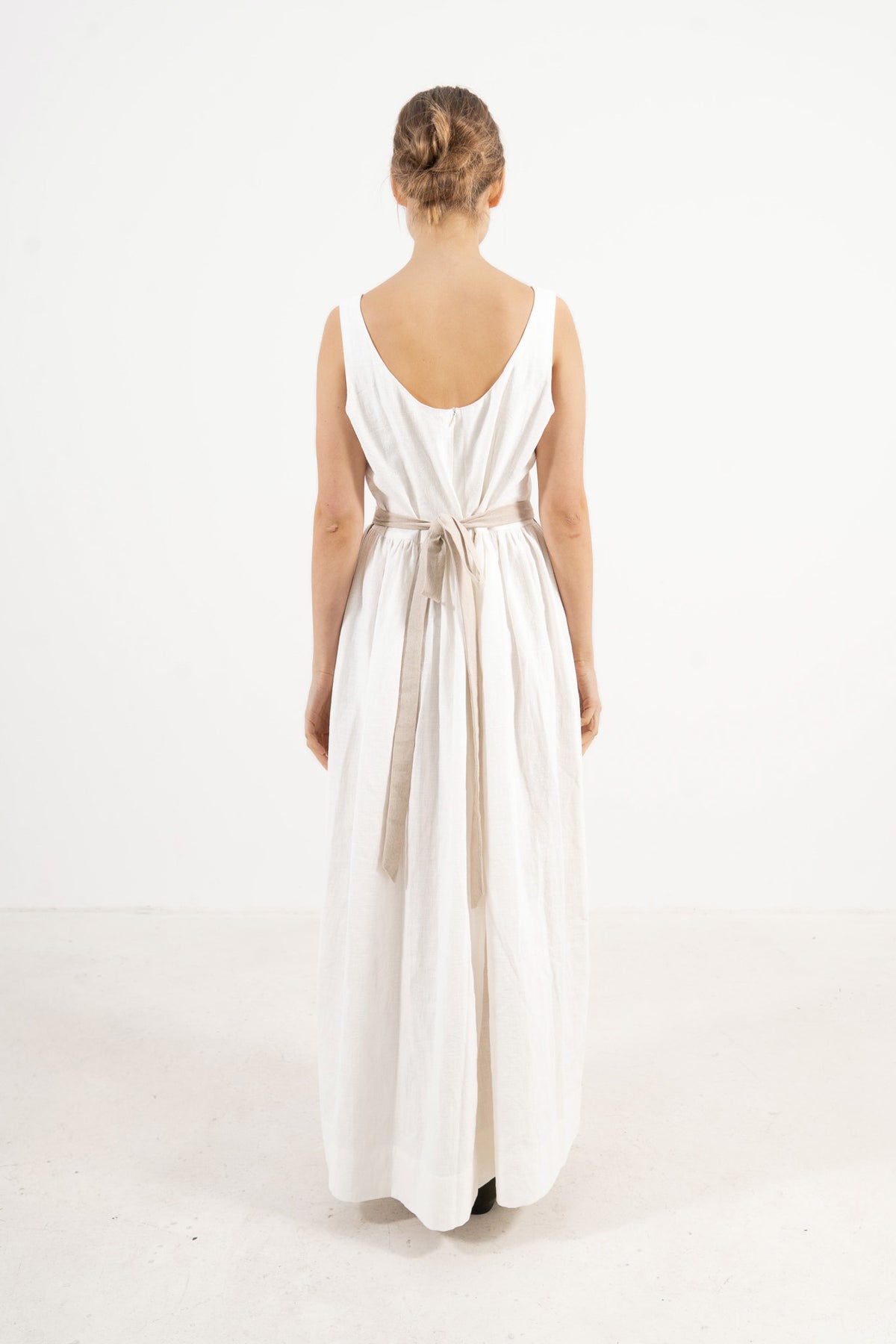 Back view of the long apron on a model, showcasing the delicate tie straps and the fine craftsmanship of the piece.