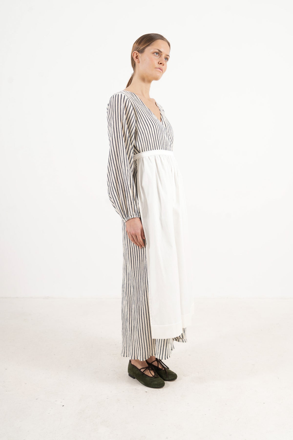 Studio lookbook portrait highlighting the relaxed fit, clean silhouette, and delicate volants of the MOCHA cotton apron.