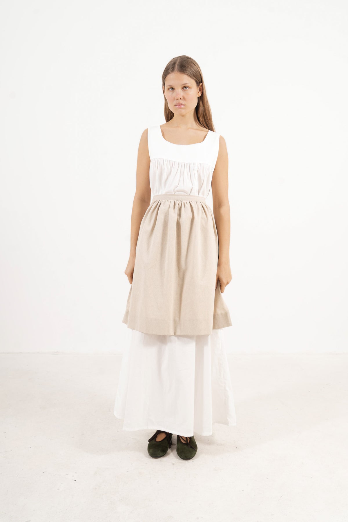 Front view lookbook image featuring a model wearing the ruffled Le Tablier mid apron in beige cotton by MOCHA, inspired by the quiet poetry of home.