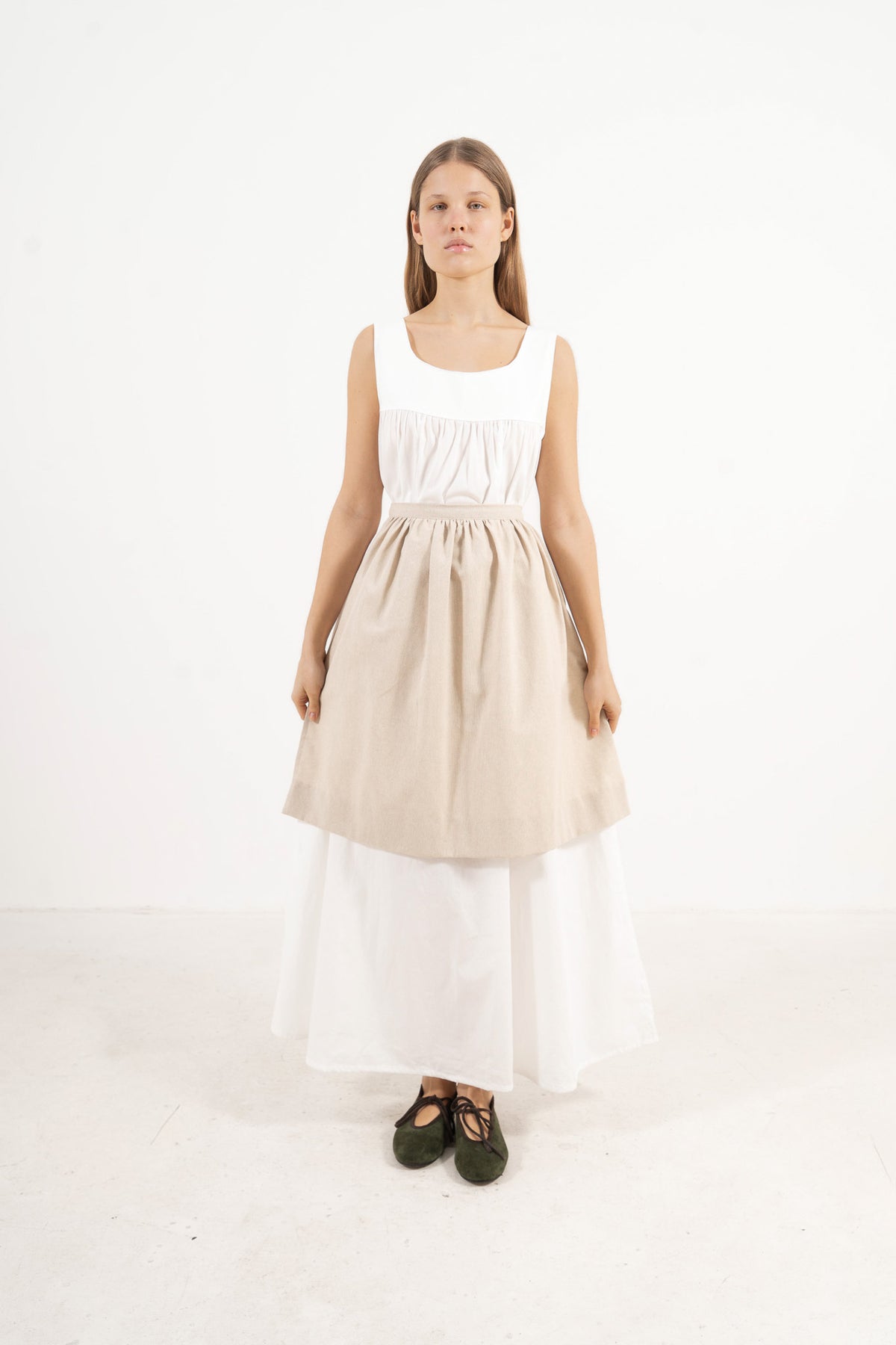 Front view lookbook image featuring a model wearing the ruffled Le Tablier mid apron in beige cotton by MOCHA, inspired by the quiet poetry of home.