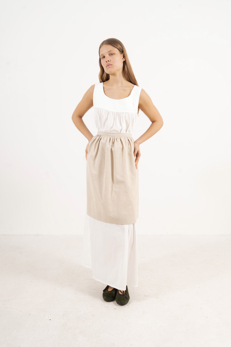 Front view lookbook image featuring a model wearing the ruffled Le Tablier mid apron in beige cotton by MOCHA, inspired by the quiet poetry of home.