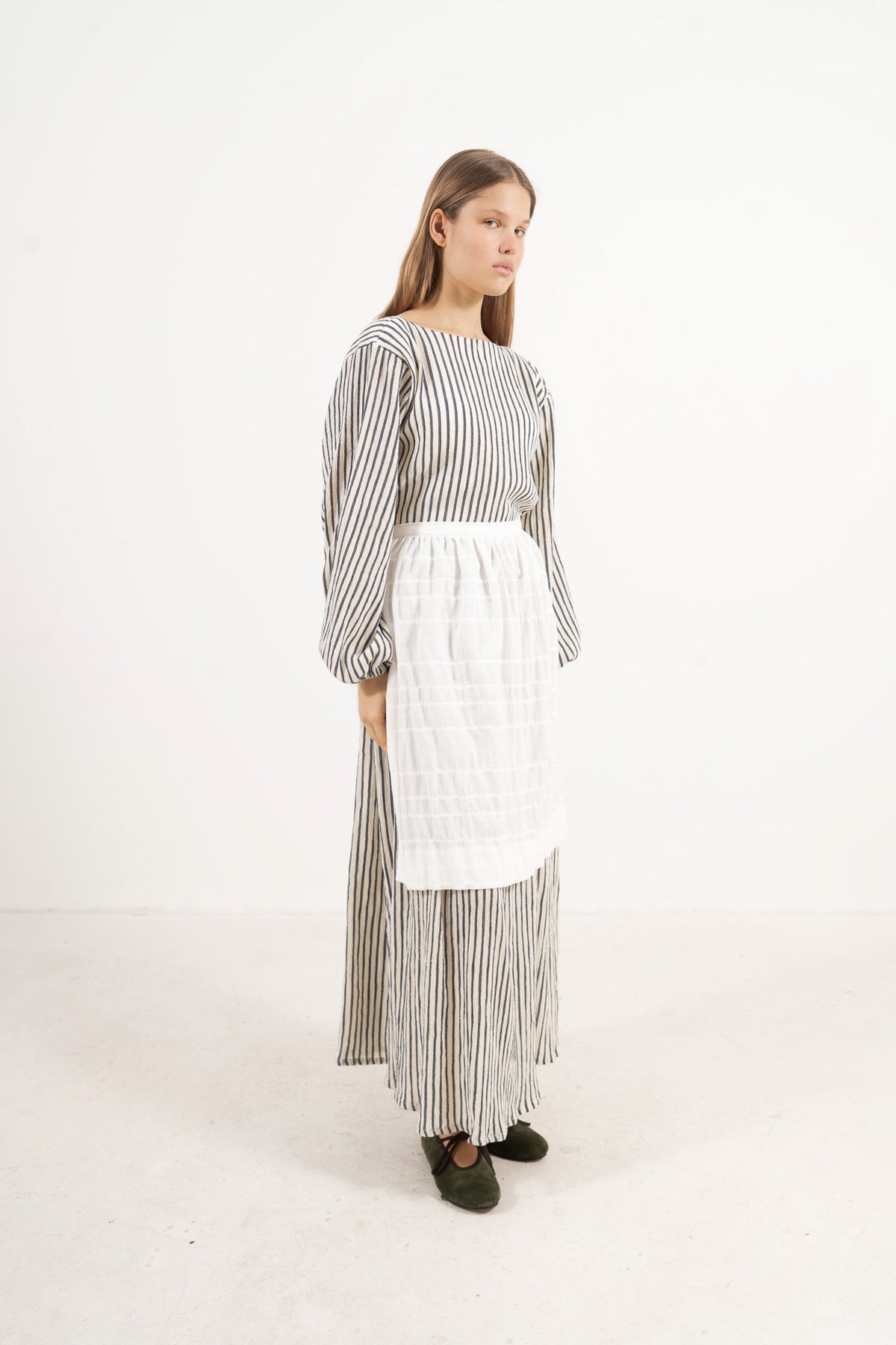 Side profile capture of the pure cotton mid apron, illustrating how it serves as an elegant accessory that brings charm and character to everyday moments.