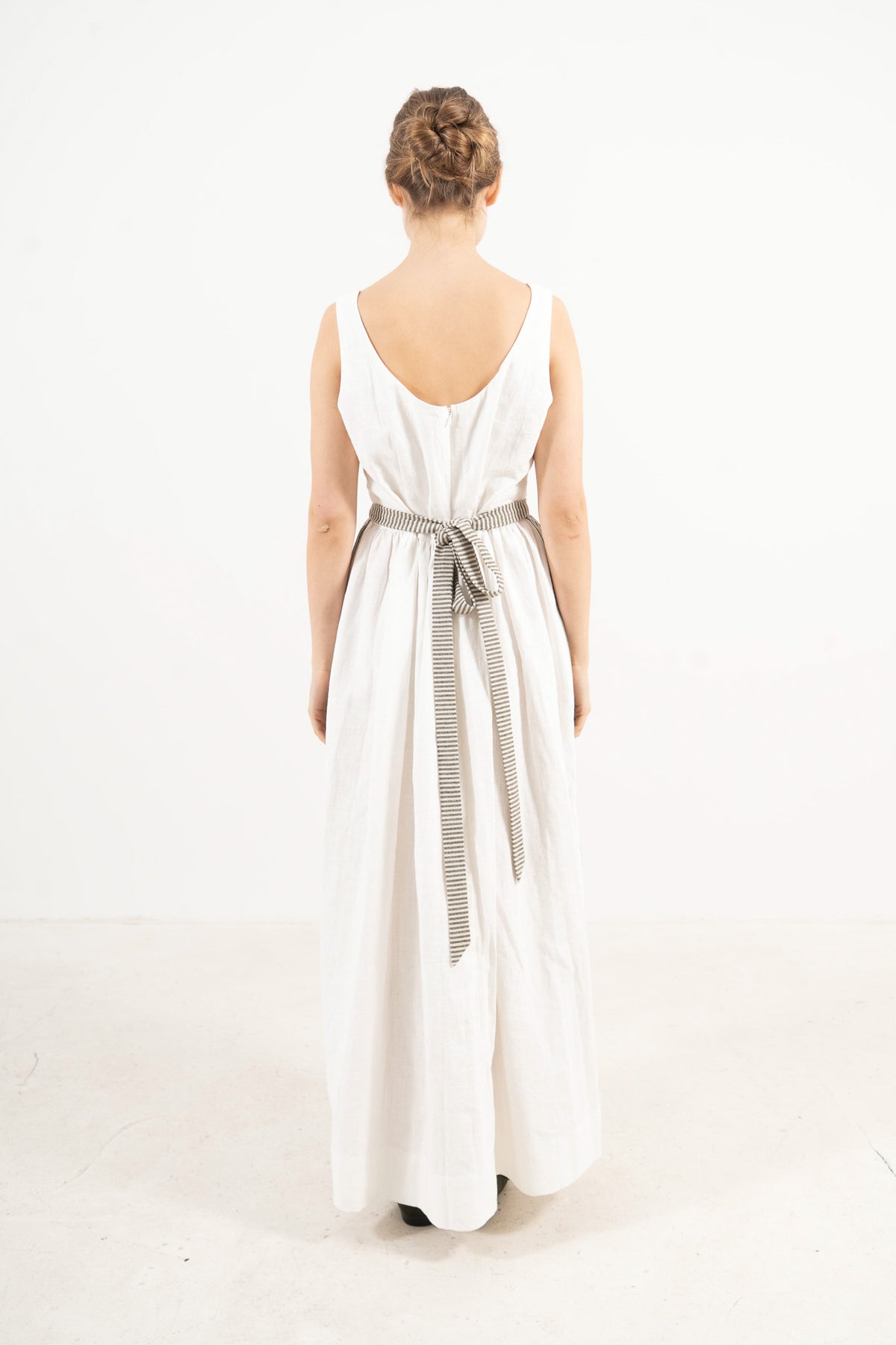 Back view of the striped mid apron on a model, showcasing the delicate tie straps and the fine craftsmanship of the piece.