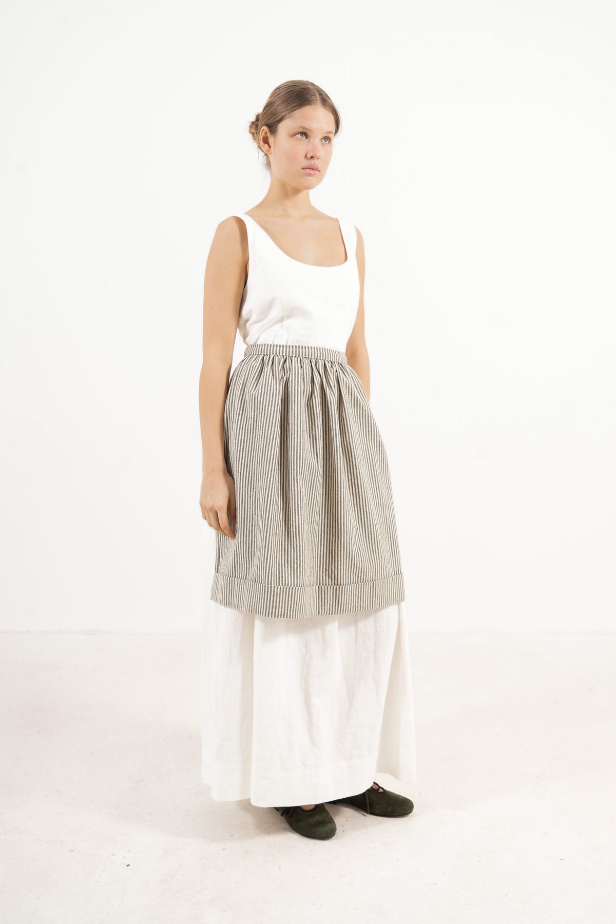 Studio lookbook portrait highlighting the relaxed fit, clean silhouette, and delicate volants of the MOCHA striped cotton apron.