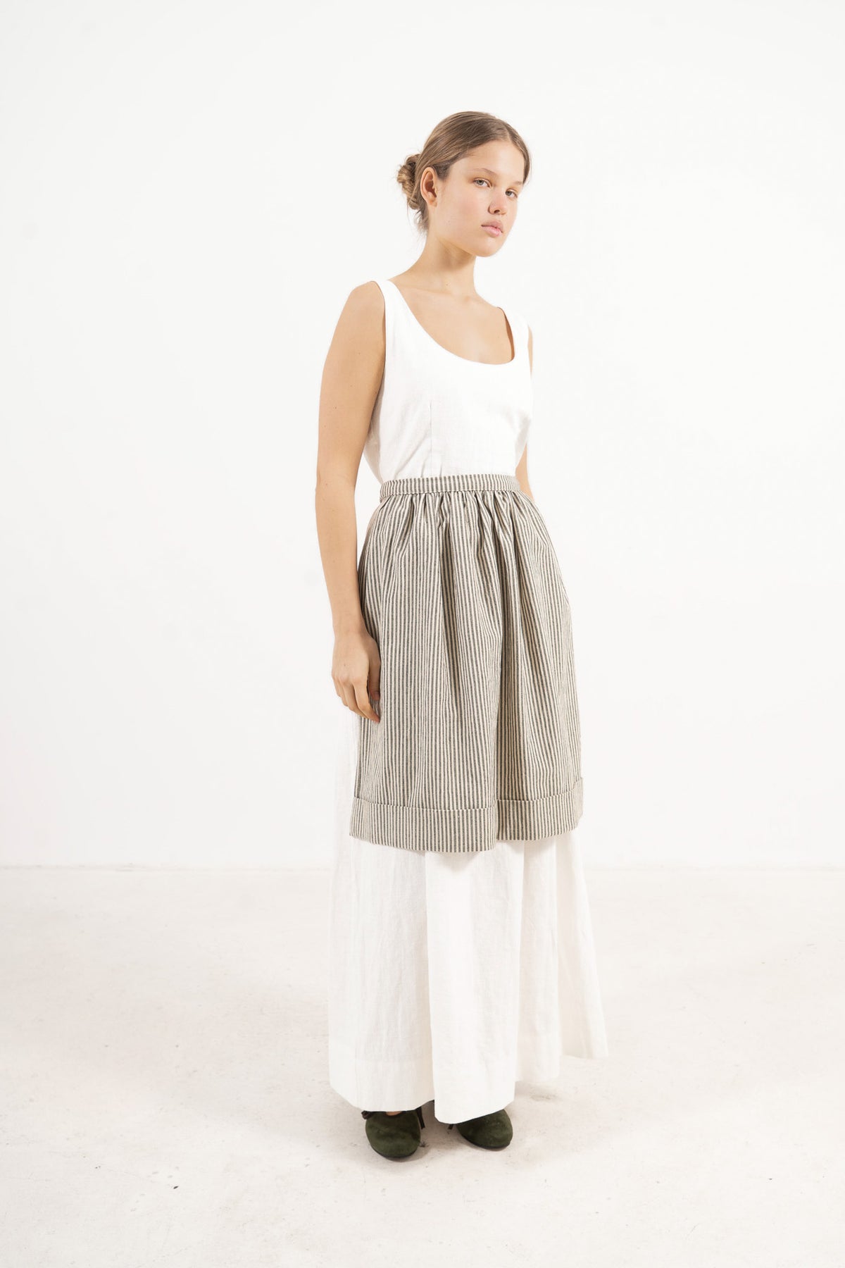 Side profile capture of the striped cotton mid apron, illustrating how it serves as an elegant accessory that brings charm and character to everyday moments.