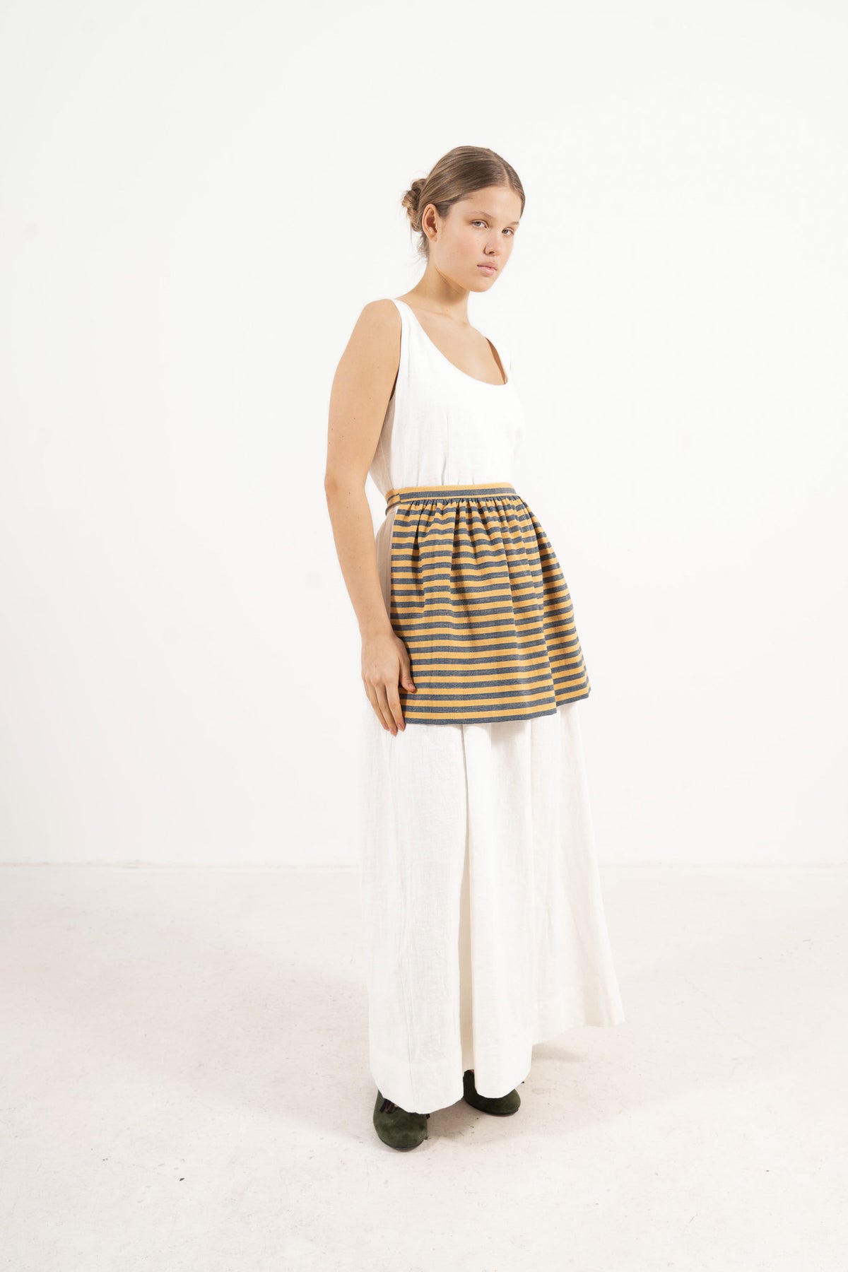 Side profile capture of the striped cotton mini apron, illustrating how it serves as an elegant accessory that brings charm and character to everyday moments.