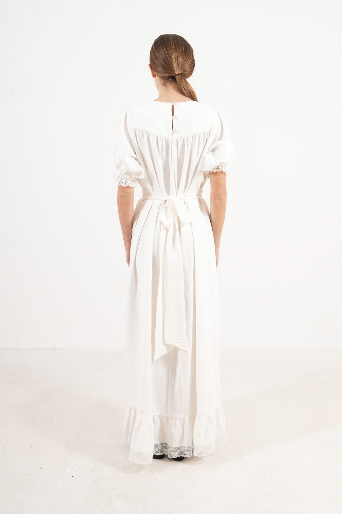 Back view of the mid apron on a model, showcasing the delicate tie straps and the fine craftsmanship of the piece.