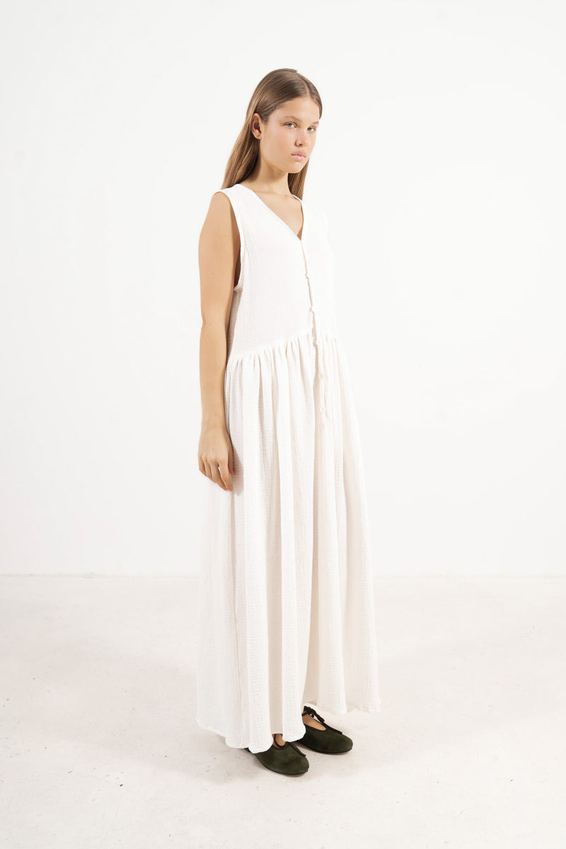 A poetic side angle view of the luxury soft cotton MOCHA Nuage garment, showcasing its light, timeless silhouette cascading softly against a white backdrop.