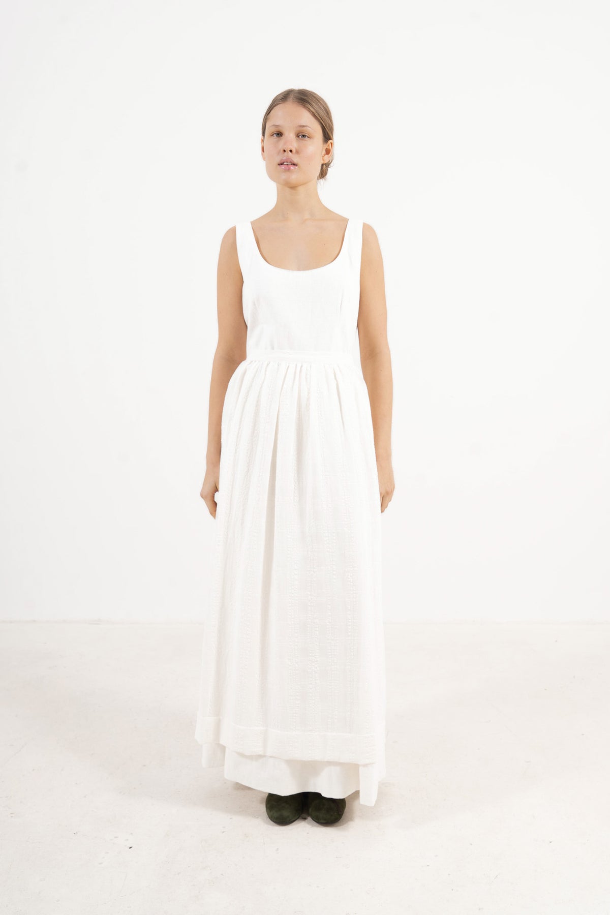 Le Tablier Long Apron from the POÈME La Cuisine line by MOCHA, highlighting the clean silhouette and delicate volants in a front lookbook shot.