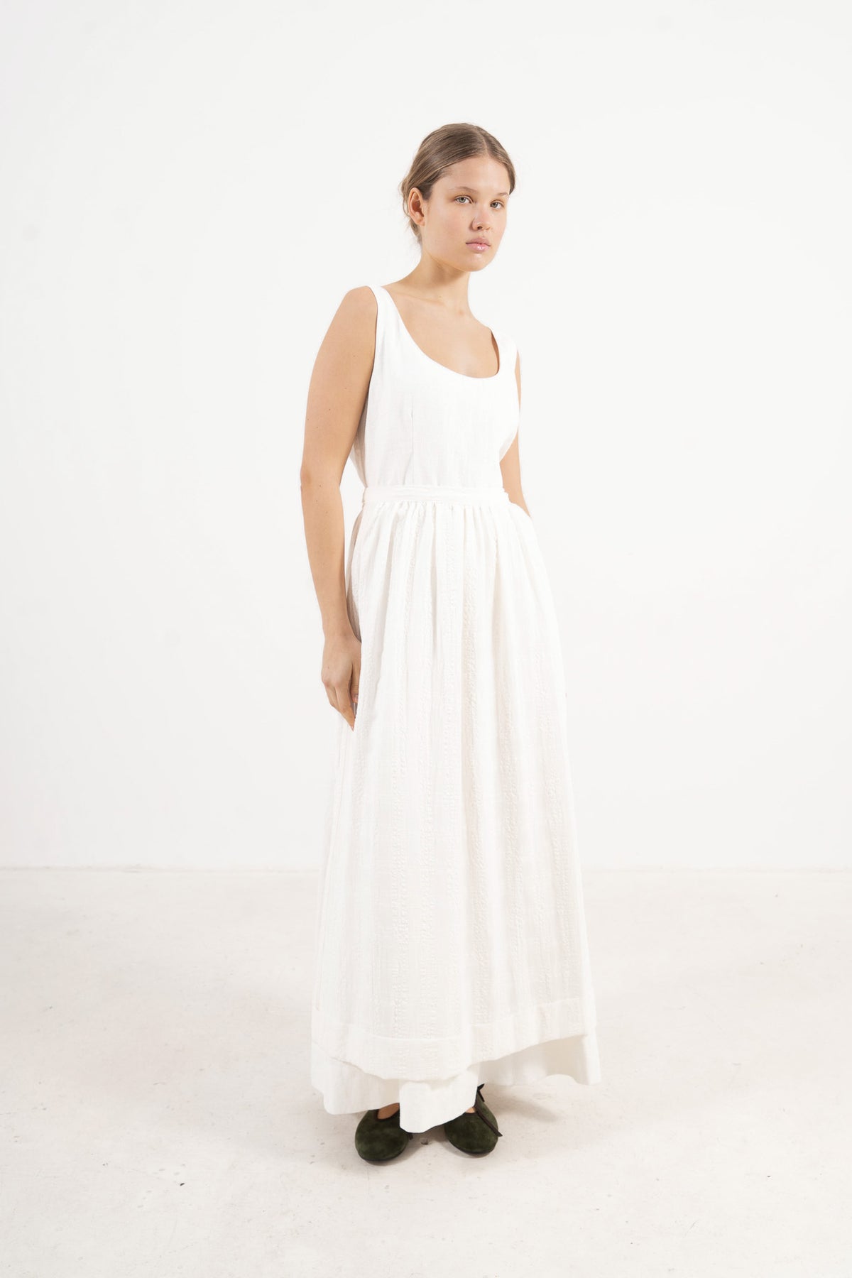 Le Tablier Long Apron from the POÈME La Cuisine line by MOCHA, highlighting the clean silhouette and delicate volants in a front lookbook shot.