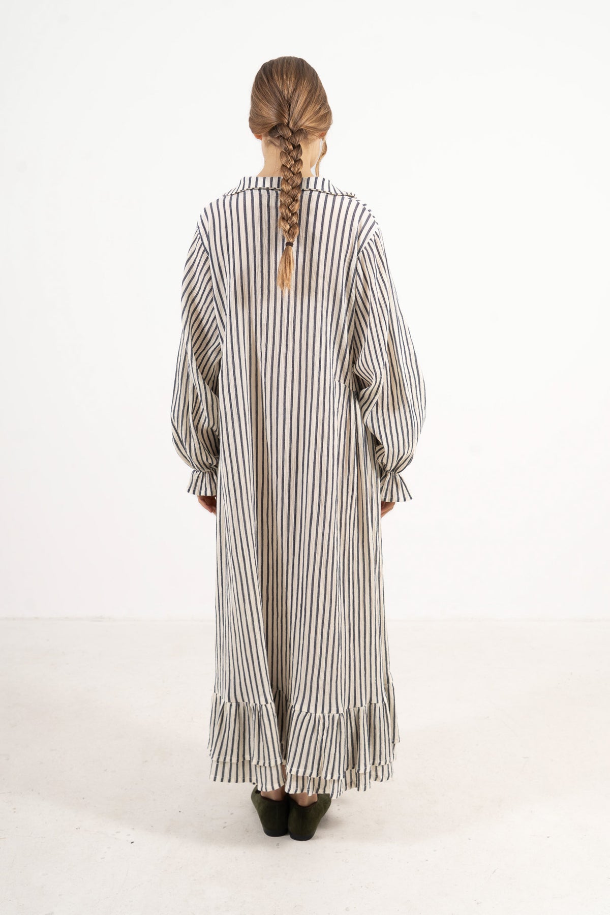 Back view of the timeless striped cotton dress on a model, capturing a gentle aesthetic inspired by air, movement, and calm days.
