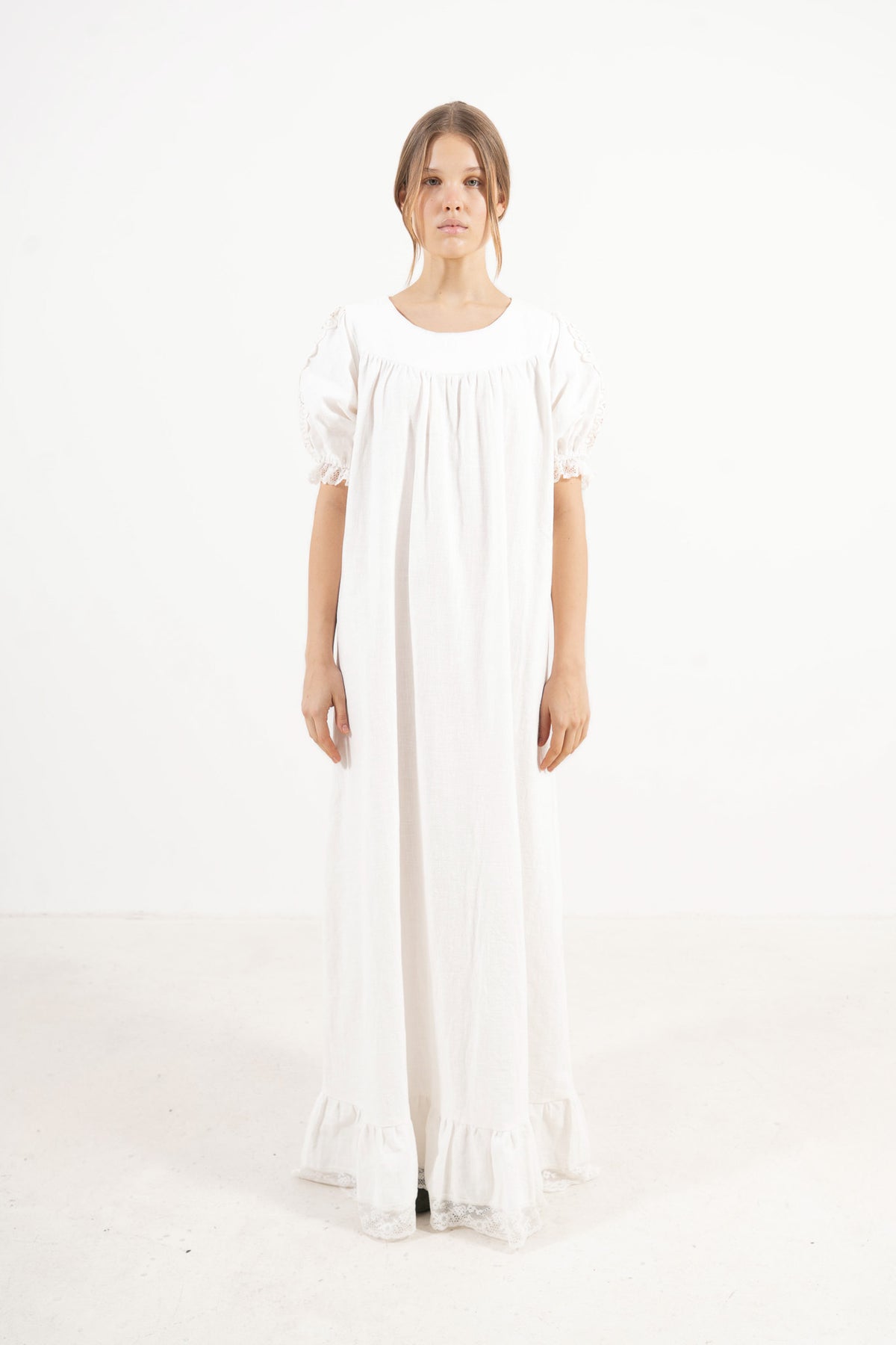 Front view studio portrait featuring a model in the white Éloise long dress by MOCHA, capturing its effortless elegance and gentle movement.